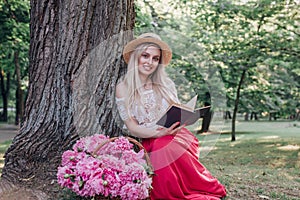 Beautiful woman on straw hat reading a book in the garden