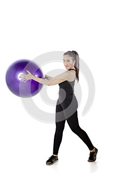 Beautiful woman stretching with fitness ball on studio