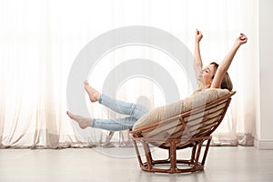 Beautiful woman stretching in papasan chair at home, space for text