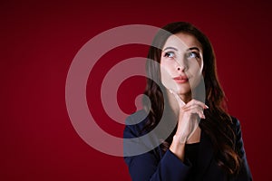 Beautiful woman in suit on a red background with a pensive look