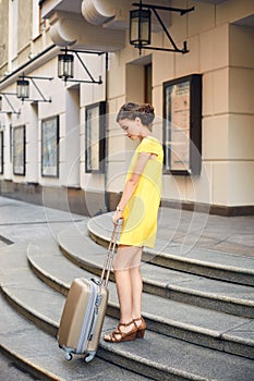 Beautiful woman with the suitcase at the entrance to the hotel