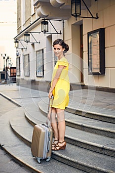 Beautiful woman with the suitcase at the entrance to the hotel