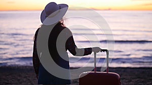 Beautiful woman with a suitcase on the sunny beach