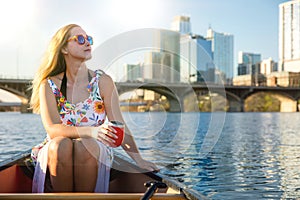 Beautiful woman on a summer day enjoying a relaxing boat ride on lake in american city on a sunny day, recreational lifestyle