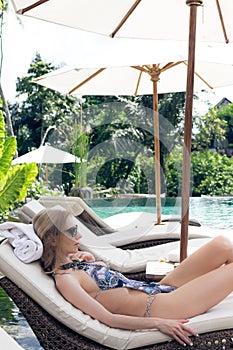 Beautiful woman sunbathing in swimming pool. Luxury model at the pool.
