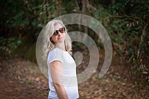 Beautiful woman in sunglasses, in the forest, looking at the camera photo