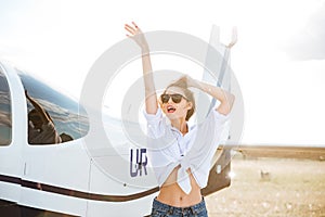 Beautiful woman in sunglasses posing near a plane