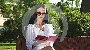 Beautiful woman in sunglasses read book in park