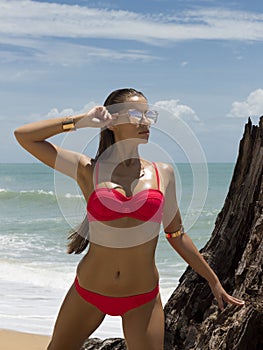 Beautiful woman in sunglasses and red bikini on beach. Fashion look. lady