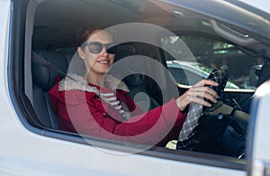 Beautiful woman with sunglasses sit in car and look at camera through window of car also look at camera with smiling in concept of