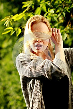 Beautiful woman in the sunny forest, covered her face with hair, fooled.