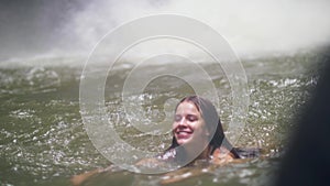 Beautiful woman swimming in mountain lake and water splash on background. Tourist woman bathing in fresh water from
