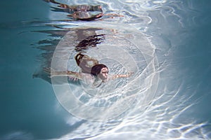 Beautiful woman swims underwater in the pool