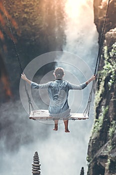 Beautiful woman swings near waterfall in the jungle of Bali island, Indonesia.