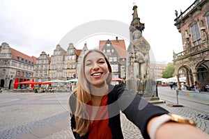 Beautiful woman takes self portrait in Bremen Market Square with Roland statue, Bremen, Germany