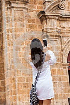 Beautiful woman taking pictures of the San Pedro Claver church located in the walled city of Cartagena de Indias