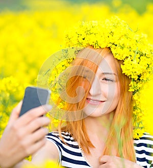 Beautiful woman taking selfie picture of herself in yellow field with natural background