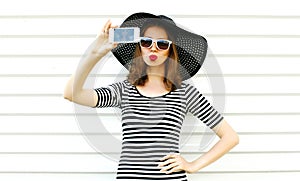 Beautiful woman taking selfie picture by phone blowing red lips sending sweet air kiss on white wall background