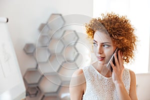 Beautiful woman talking on cell phone in office