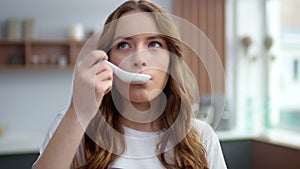 Beautiful woman tasting hot meal in home kitchen. Girl smelling seafood indoors.