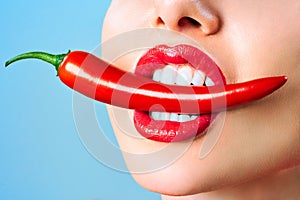 Beautiful woman teeth eating red hot chili pepper Dental clinic patient. Image symbolizes oral care dentistry