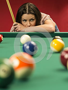 Beautiful woman thinking about her next pool shot