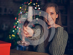 Beautiful woman toasting with red wine. Selective focus. Christmas lights in the background