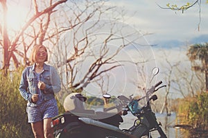 beautiful woman toothy smiling with happiness standing beside small enduro motorcycle at jungle field