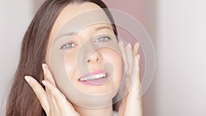 Beautiful woman touching her face, applying organic cosmetic cream with facial massage lines, glowing healthy skin and