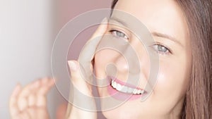 Beautiful woman touching her face, applying organic cosmetic cream with facial massage lines, glowing healthy skin and