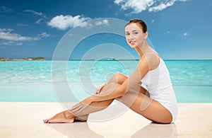 Beautiful woman touching her legs on summer beach