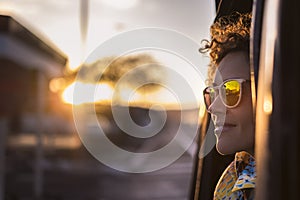 Beautiful woman travel on a car looking outside and enjoy the light of the golden sunset on her face. nice lifestyle and peaceful