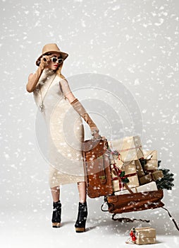 Beautiful woman traveler in hat with big open leather retro bag full of christmas present gifts