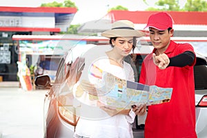 Beautiful woman traveler holding touristic map while asking gas station attendant staff for finding right direction, cute female