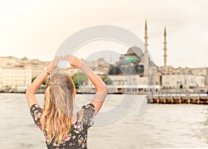 Beautiful woman traveler makes heart shape over New Mosque