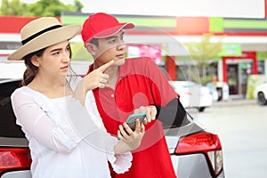 Beautiful woman traveler riding using mobile phone navigation while asking gas station attendant staff for finding right direction