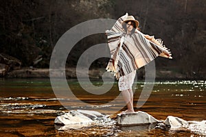 Beautiful woman traveler standing on rocks in river and playing