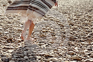 Beautiful woman traveler walking barefoot at river beach, legs
