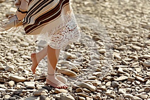 Beautiful woman traveler walking barefoot at river beach, legs