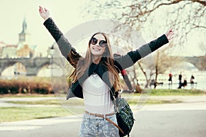 Beautiful woman traveling in Europe and walking on park in Prague. Girl having fund and holding hands up outdoors