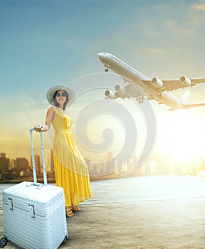 Beautiful woman and traveling luggage standing in airport terminal with passenger plane flying over sky