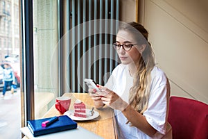 Beautiful woman in trendy glasses checking e-mail on mobile phone