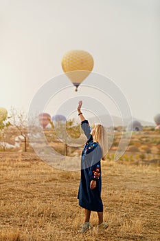 Beautiful Woman Trying To Reach Hot Air Balloon In Sky With Hand