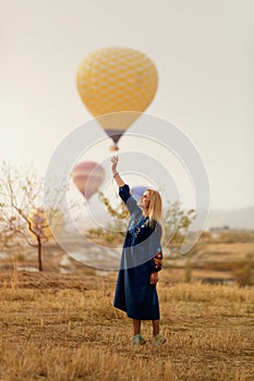 Beautiful Woman Trying To Reach Hot Air Balloon In Sky With Hand