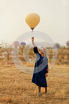 Beautiful Woman Trying To Reach Hot Air Balloon In Sky With Hand