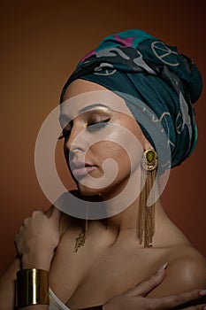 Beautiful woman with turban. Young attractive female with turban and golden accessories. Beauty fashionable woman