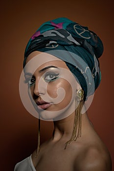 Beautiful woman with turban. Young attractive female with turban and golden accessories. Beauty fashionable woman