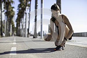 Beautiful woman tying shoes on a bike lane in Barcelona beach & x28;SPAIN