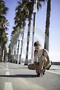 Beautiful woman tying shoes on a bike lane in Barcelona beach & x28;SPAIN