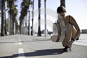 Beautiful woman tying shoes on a bike lane in Barcelona beach & x28;SPAIN